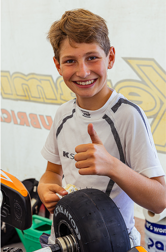 Młody uczestnik Racing Future Academy z kciukiem w górę - sukces w programie STEAM